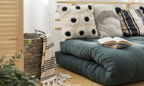 books-on-scandinavian-futon-with-pillows-in-elegant-bedroom-interior-real-photo